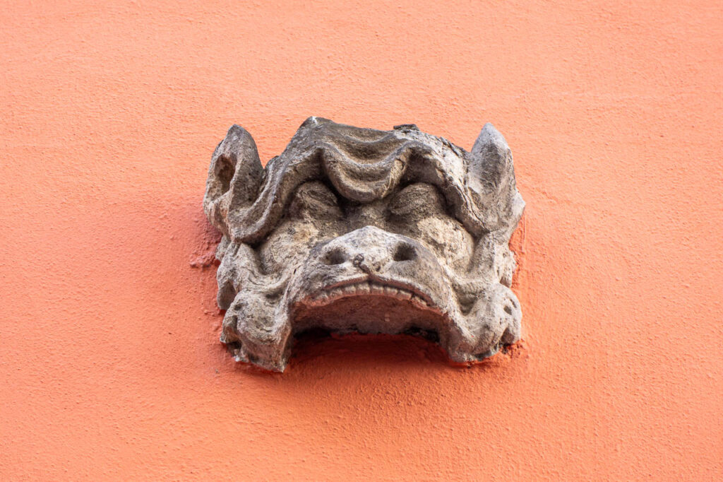 Grinkopf an einer orangen Hauswand